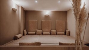 A room with a large bed, multiple pillows, a vase with dried plants, and recessed ceiling lighting.