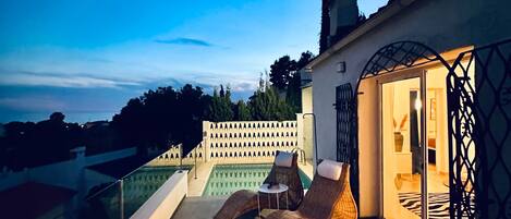 Una terraza en la azotea con piscina, sillones de descanso y una zona de estar cubierta.