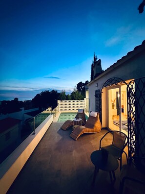 A rooftop terrace with a pool, lounge chairs, and a covered seating area.