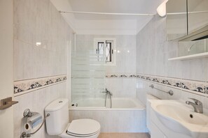 A bathroom with a toilet, a bathtub, and a sink.