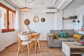 A modern living room with a grey sofa, wooden dining table, and chairs. - Naufragos Beach 1 (Torrevieja)