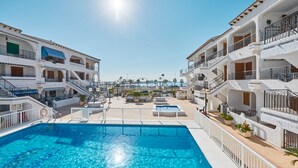 Une grande piscine entourée d’immeubles à plusieurs étages, dotés de balcons et d’espaces de détente en plein air.