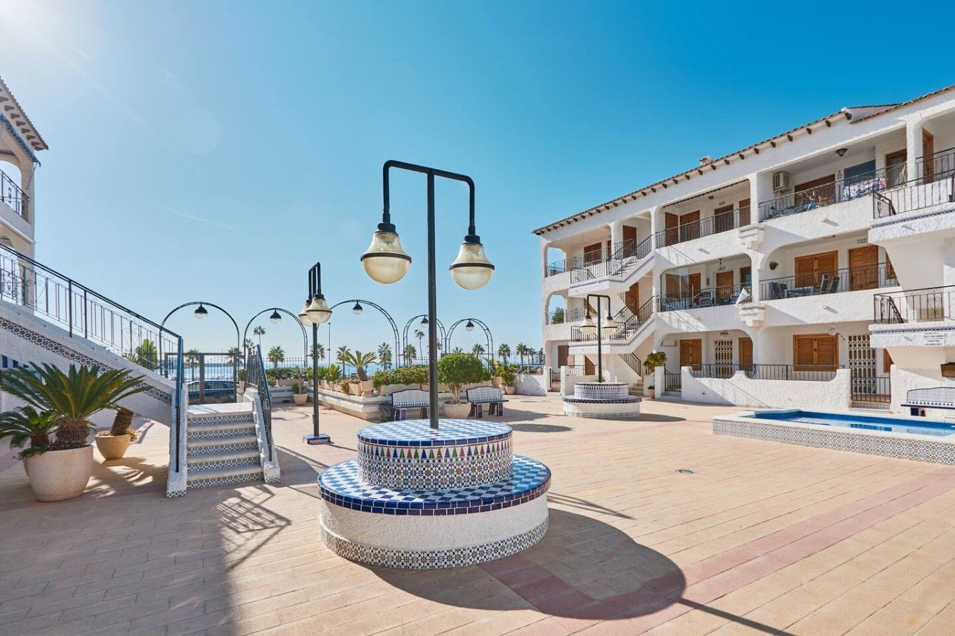 Een resort met een zwembad, terras en een trap naar een gebouw met meerdere verdiepingen.