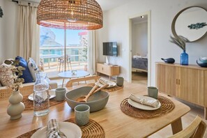 A dining area with a wooden table, woven placemats, and a large woven light fixture.