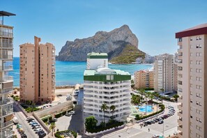 Une zone urbaine côtière caractérisée par de grands immeubles, un rond-point central et une montagne en arrière-plan.