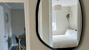 Ein Zimmer mit einem Bett, einer hängenden Pflanze und einem Essbereich mit Stühlen und einem Tisch.