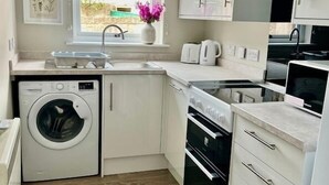 Eine kleine Küche mit Waschmaschine, Backofen und Mikrowelle.