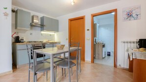 A compact kitchen with a dining area, a wooden door leading to a bathroom, and a small table with chairs. - 1 bedroom gorgeous apartment in Masso (Masso)