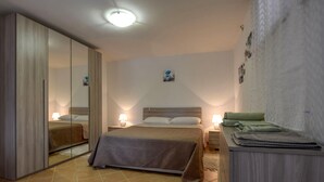 A bedroom with a bed, bedside lamps, a mirror, a wardrobe, and a small table with a lamp. - 1 bedroom gorgeous apartment in Masso (Masso)