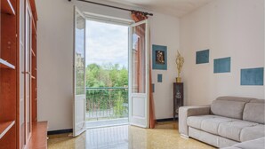 A spacious living room with a large sliding glass door leading to a balcony, a beige sofa, and a wooden cabinet. - Lovely home in Chiavari with WiFi (Chiavari)