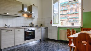 A kitchen with a window, a stove, an oven, and a dining area with a table and chairs. - Lovely home in Chiavari with WiFi (Chiavari)