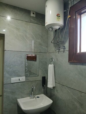 Un baño con un calentador blanco de pedestal, un lavabo y un espejo.