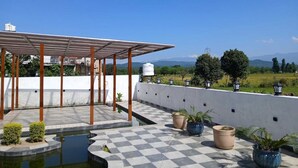Um terraço no telhado com piso xadrez, pérgola, plantas em vasos e vista da paisagem.