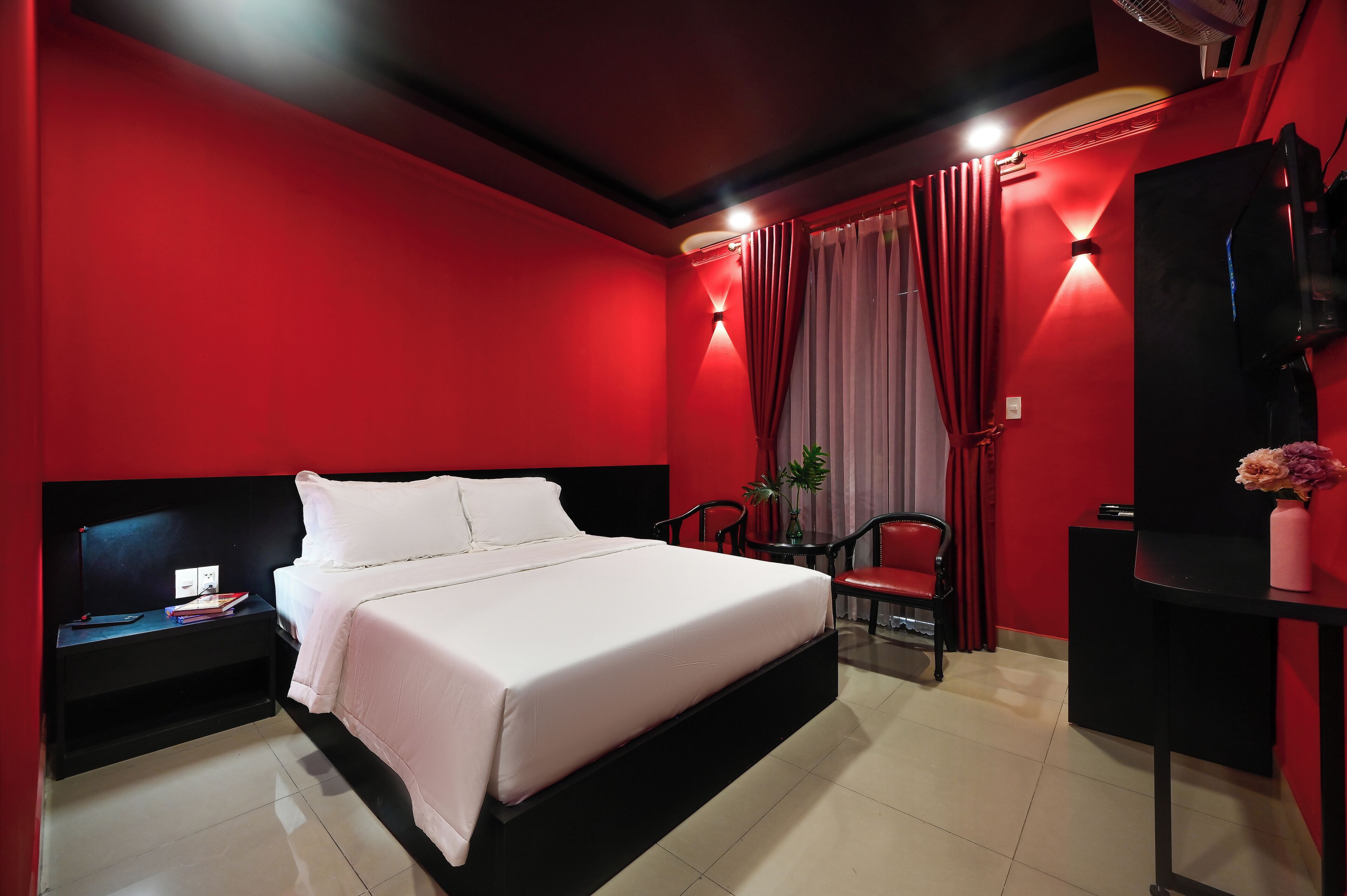 A modern hotel room with a large bed, a desk, a chair, and a TV.