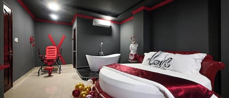 A modern bedroom with a red and white color scheme, a large bed, a red chair, a white bathtub, and a red and white wall decoration.
