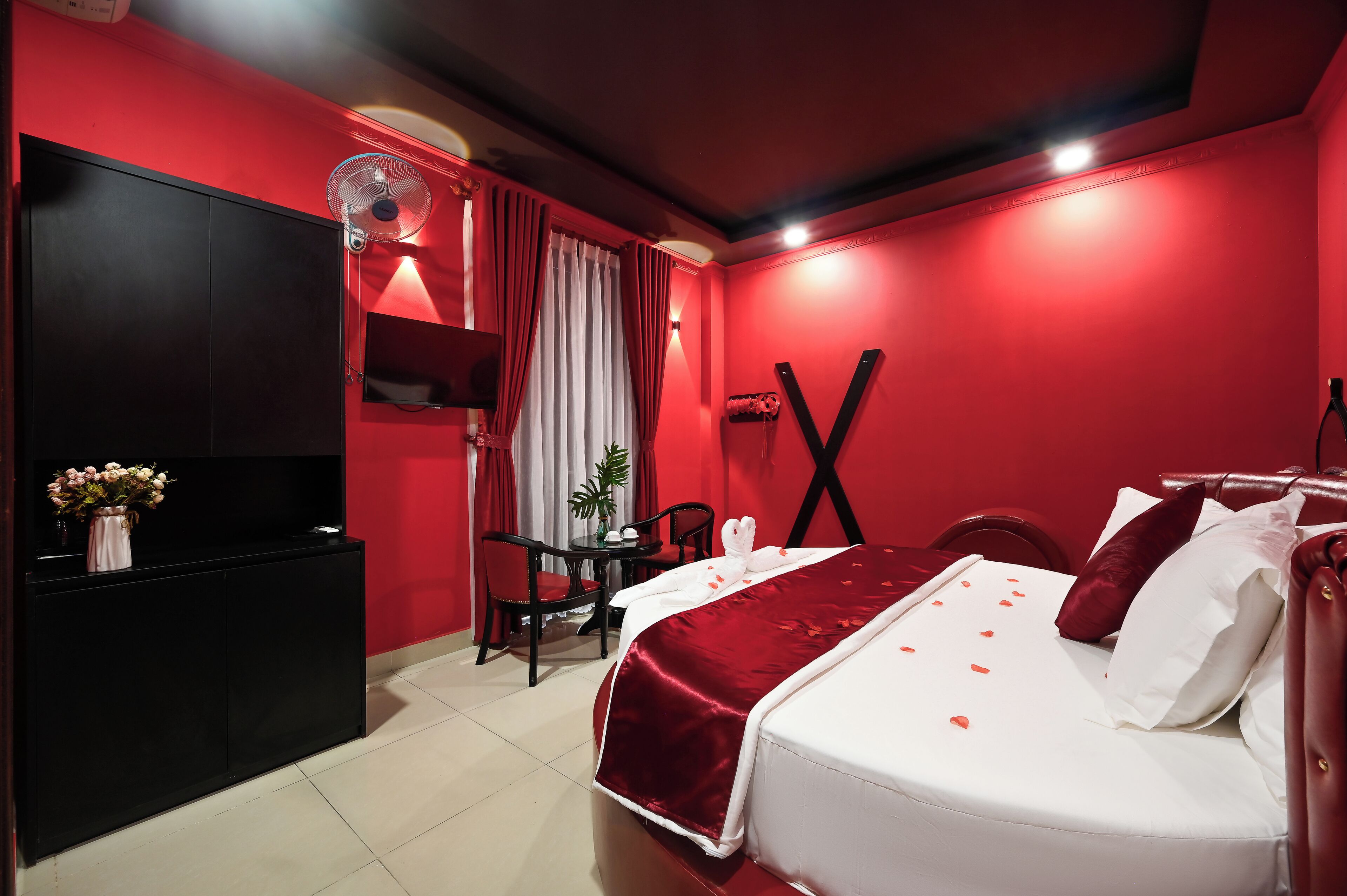 A red-themed hotel room with a bed, a desk, and a chair.