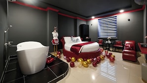 A modern bedroom with a large bed, a bathtub, and a seating area with red chairs. - Hotel Trung Mai-Tân Bình (Ho Chi Minh City)