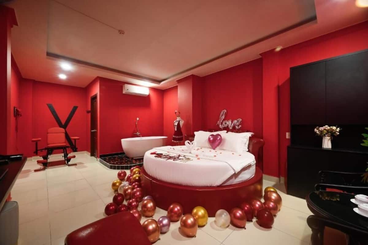 Ein rot gehaltenes Schlafzimmer mit einem Bett, einem Schminktisch, einem Sessel und einem Schreibtisch.