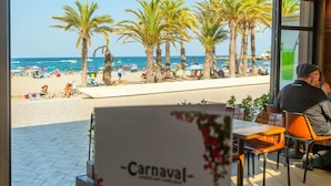 En restaurant ved stranden med udendørs siddepladser med udsigt over stranden og havet.