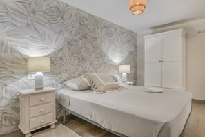 Una camera da letto con un letto, comodini, un armadio e una parete decorata con un motivo a foglie.