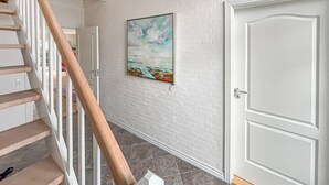 A hallway with a white brick wall, a wooden staircase, and a door with a keyhole. - Beautiful home in Esbjerg V with WiFi (Esbjerg V)