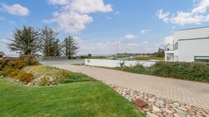 A paved pathway leading to a modern building with a white exterior, surrounded by greenery and a clear sky. - Beautiful home in Esbjerg V with WiFi (Esbjerg V)