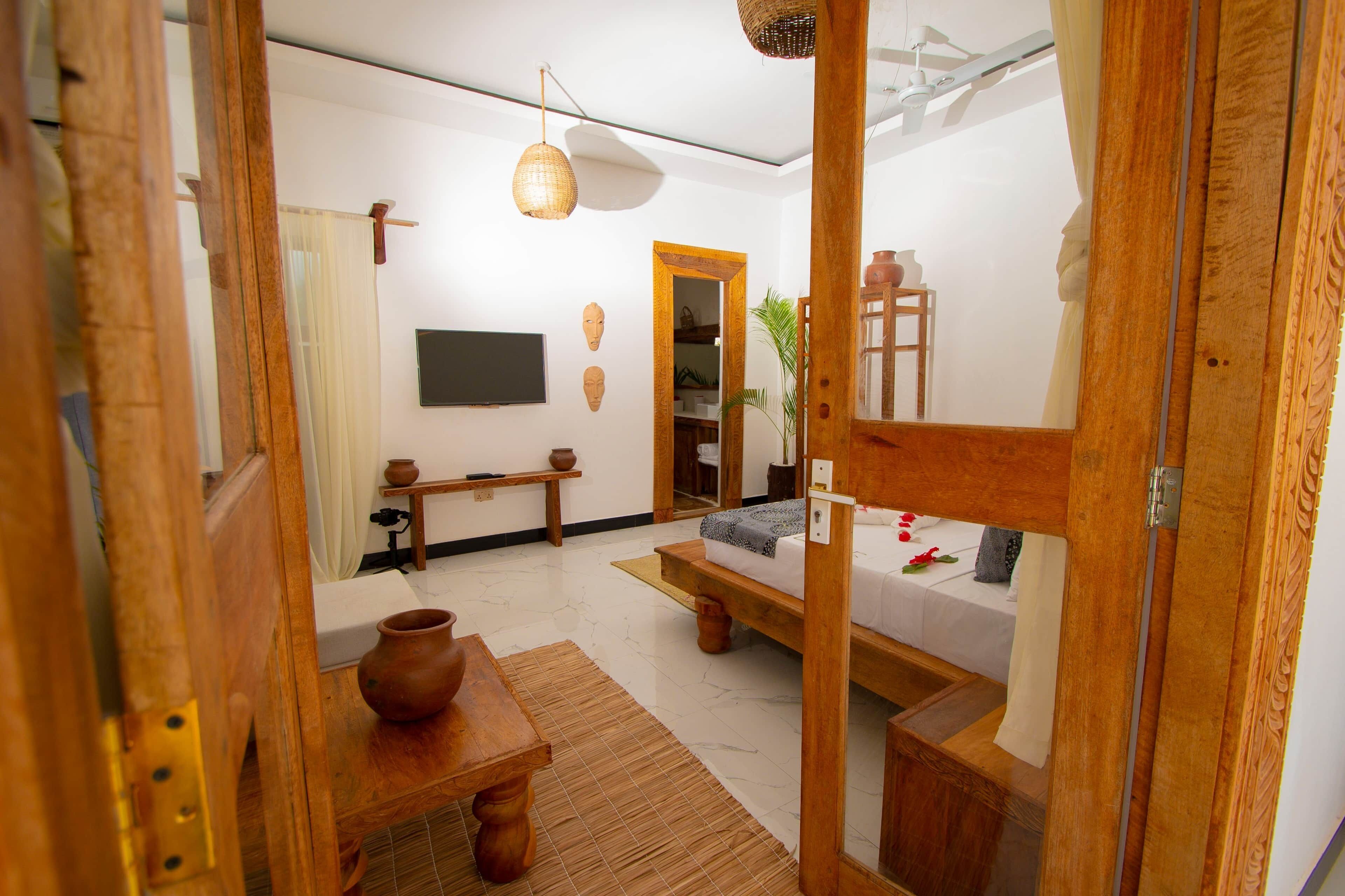 A traditional Japanese-style room with tatami flooring, a low wooden bed, a small table with a pottery piece, and a hanging light fixture.