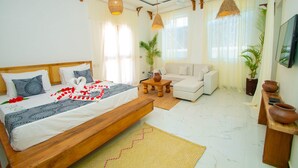 A spacious bedroom with a large bed, a sofa, and a TV.
