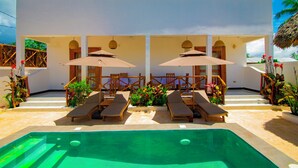 A modern building with a swimming pool, sun loungers, and umbrellas.
