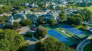 Ett flygbildsbild av ett bostadsområde med hus, en tennisbana och en parkeringsplats.