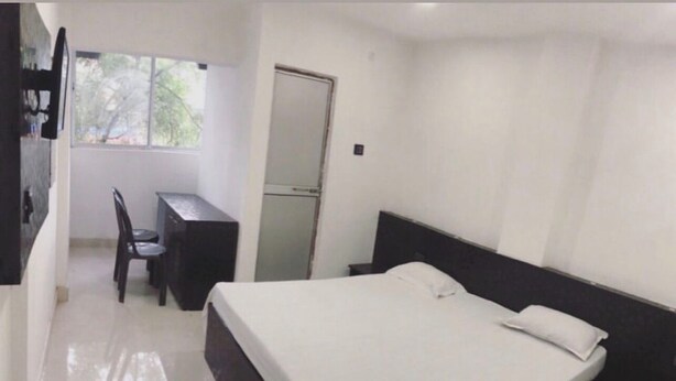 A bedroom with a bed, a desk, and a chair. - HOTEL SIDHU  (Jamshedpur)