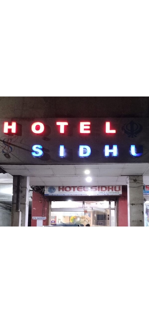Ein Hotelschild mit dem Schriftzug 'HOTEL SIDHU' in leuchtendem Rot und Blau.
