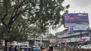 A busy street scene with a large billboard advertising a car. - HOTEL SIDHU  (Jamshedpur)
