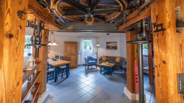 A rustic interior with a dining area, a sofa, and a ceiling fan. - Holiday Home 'Windmill Betty by the North Sea' with Private Terrace, Private Garden and Wi-Fi (Cuxhaven)