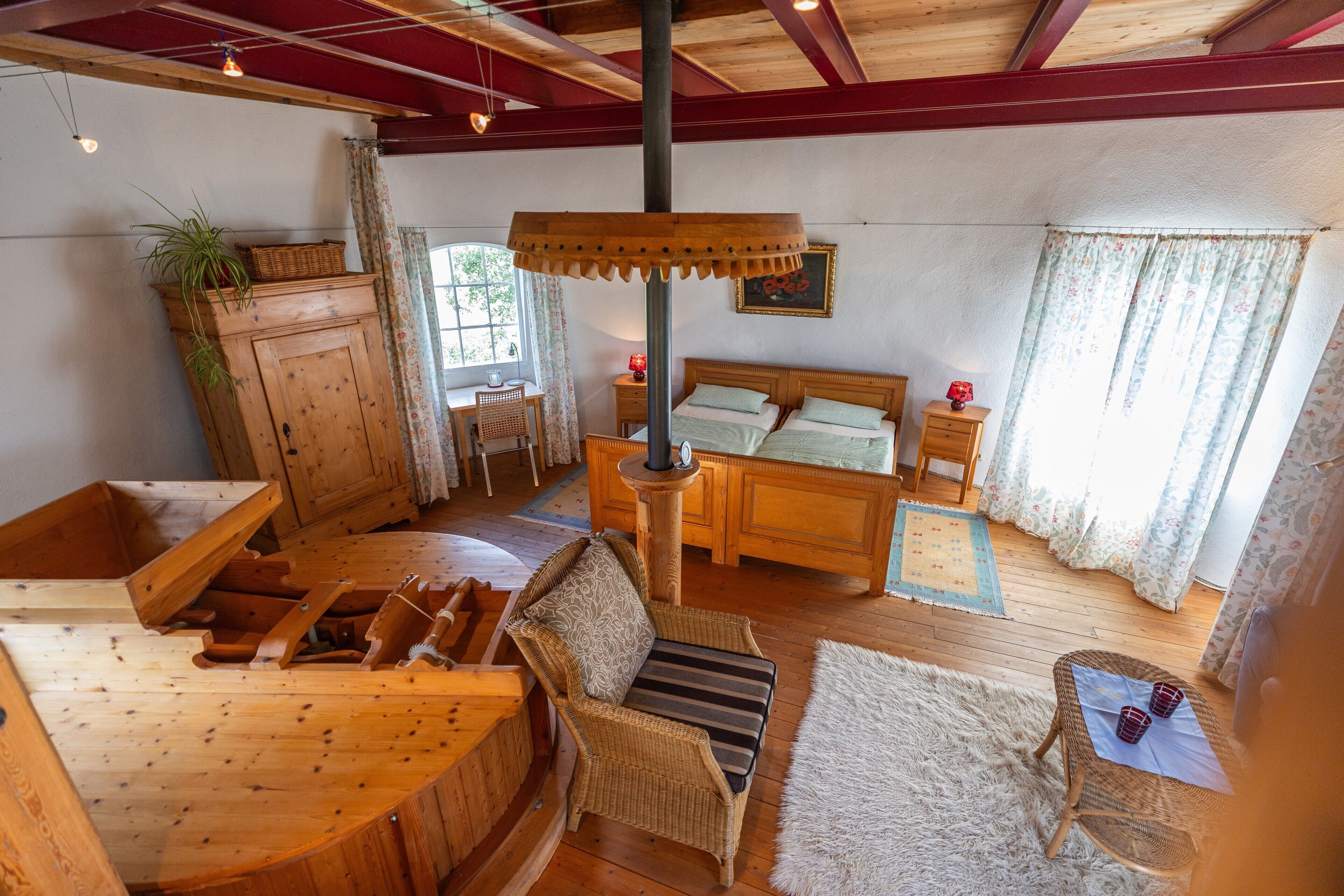 A wooden interior with a bed, wicker chair, and a dining area.