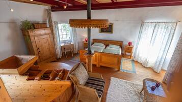 A wooden interior with a bed, wicker chair, and a dining area.