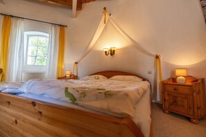 A bedroom with a wooden bed, a nightstand, a wall-mounted light fixture, and a window with curtains. - Holiday Home 'Windmill Betty by the North Sea' with Private Terrace, Private Garden and Wi-Fi (Cuxhaven)