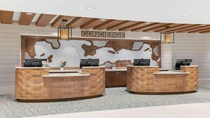 Zona de recepción con mostrador de madera, un mural con un mapa y un cartel que dice "CONCIERGE".
