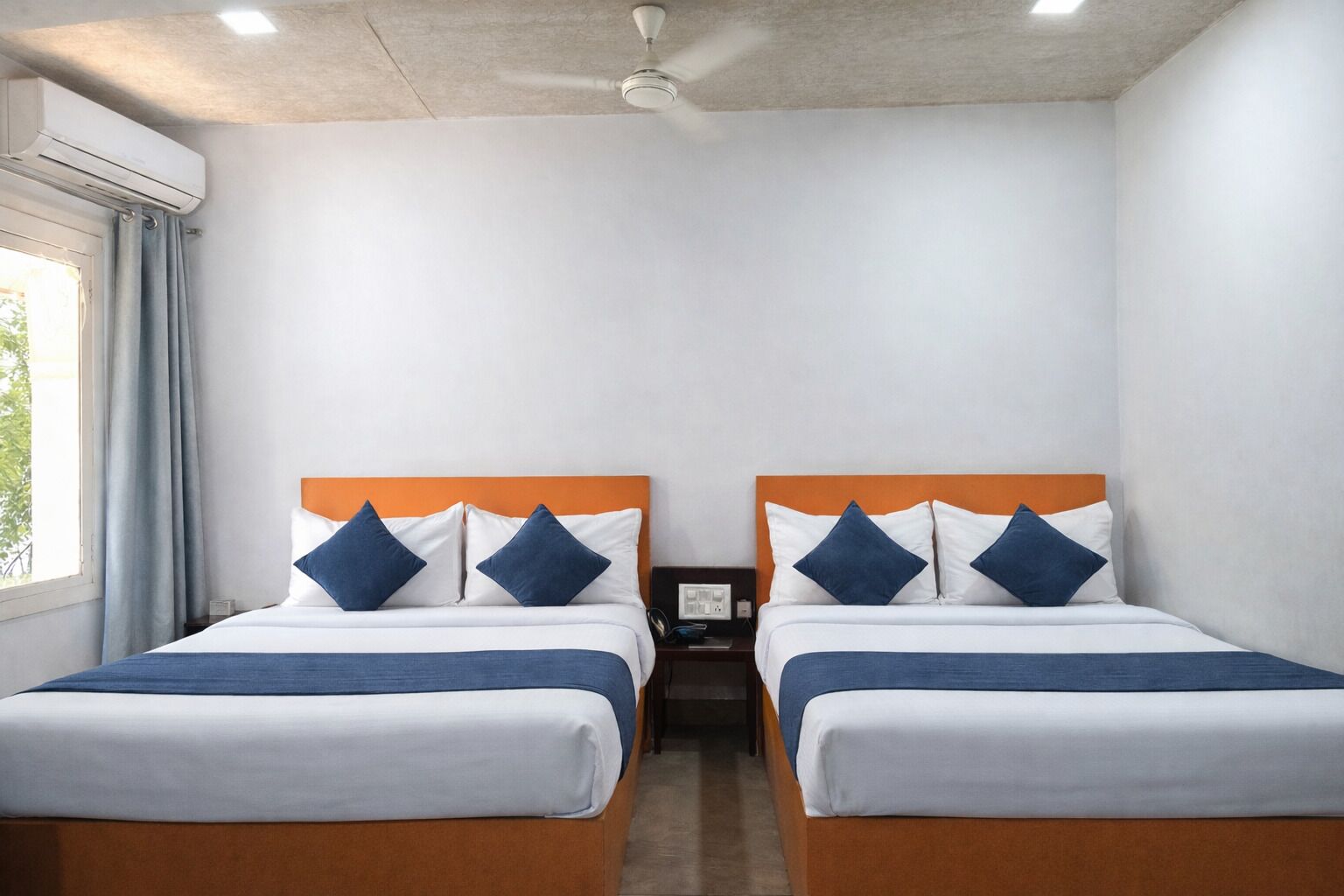 A hotel room with two beds, each with a blue and white bedspread and matching pillows.