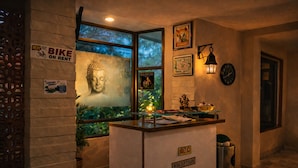 Una zona de recepción con una estatua de Buda, un letrero de alquiler de bicicletas y un reloj en la pared.
