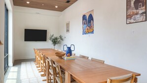 A long wooden table with chairs, a plant, and artwork on the walls.