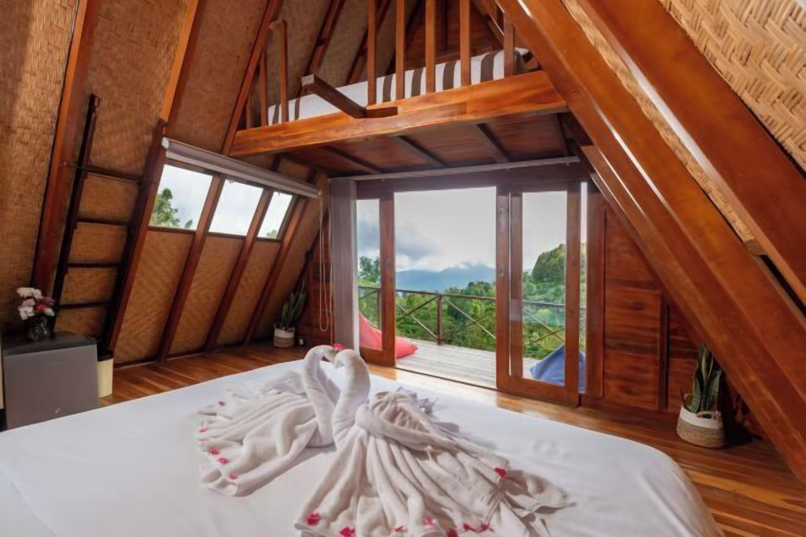Un dormitorio con cama, techo de madera y balcón con vistas.