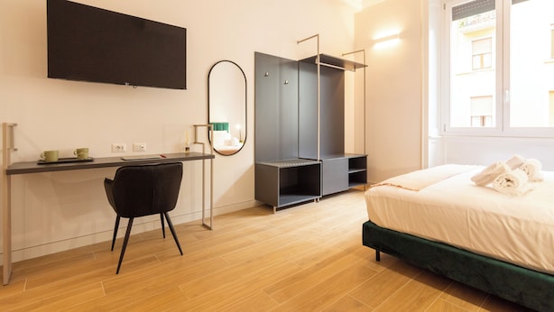 Ein modernes Hotelzimmer mit Bett, Schreibtisch mit Stuhl, Kleiderschrank und großem Fenster.