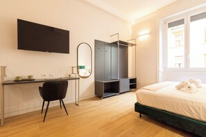 Una habitación de hotel moderna con una cama, un escritorio con silla, un armario y un ventanal grande.