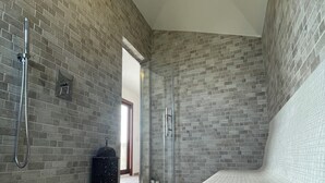 Un baño moderno con ducha, cabina de ducha con mampara de vidrio y suelo de baldosas.