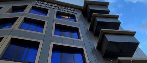 A hotel building with multiple floors, large windows, and a sign indicating it is the Al Qasr Hotel Apartments.