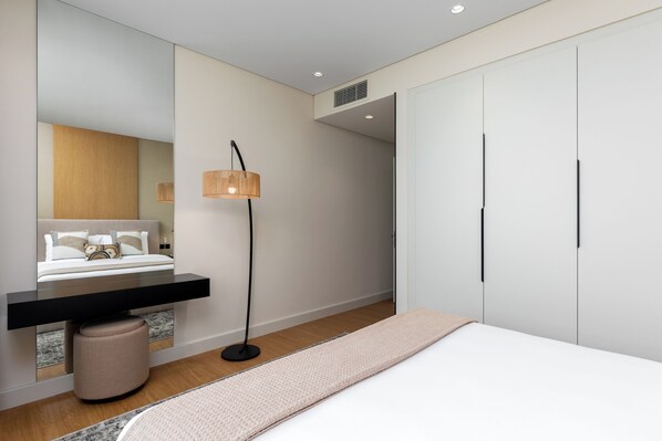 A modern bedroom with a bed, bedside table, lamp, and wardrobe. - Maison Privee - Chic Downtown Living w/ Dubai Cityscape Views (Dubai)
