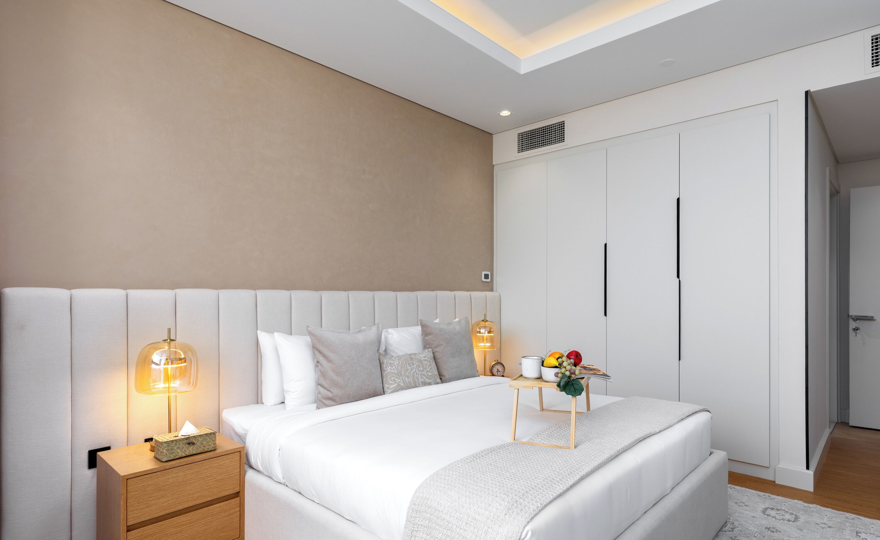 Een moderne slaapkamer met een groot bed, nachtkastjes, een nachttafeltje en een wandplank.