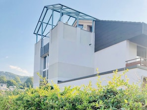 Un edificio moderno con estructura de vidrio en el techo, fachada blanca y balcón.