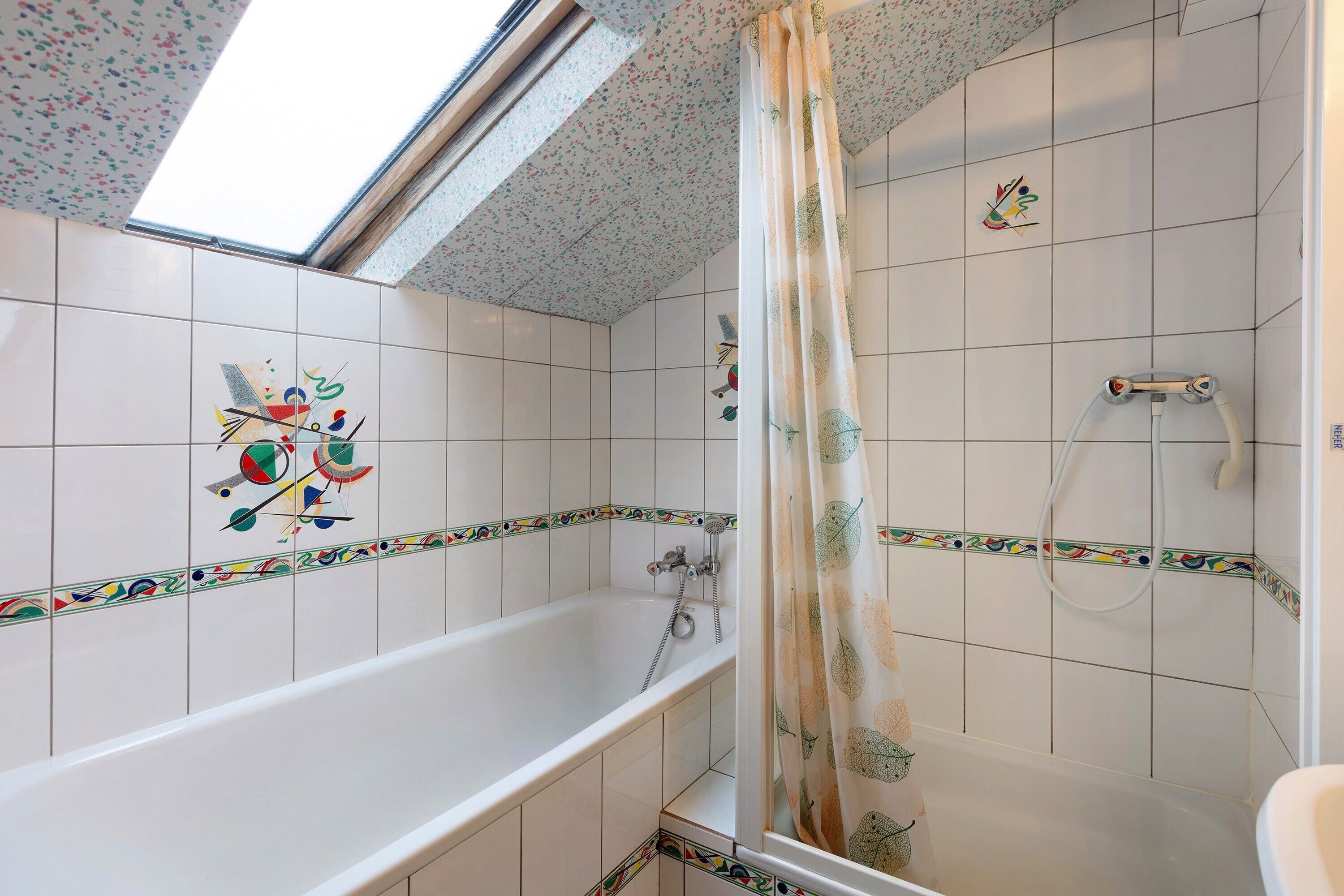 A bathroom with a bathtub, shower, and skylight.